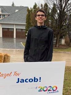 A grade 12 graduate beside his lawn sign