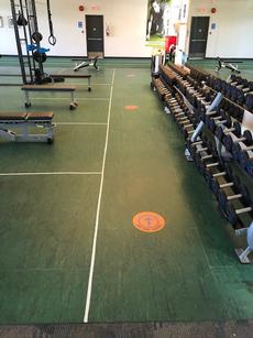 Free weights area on fitness floor with clearly marked physical distancing safe spots