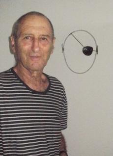 Udi Dayan standing next to a metal sculpture he did of his father Moshe